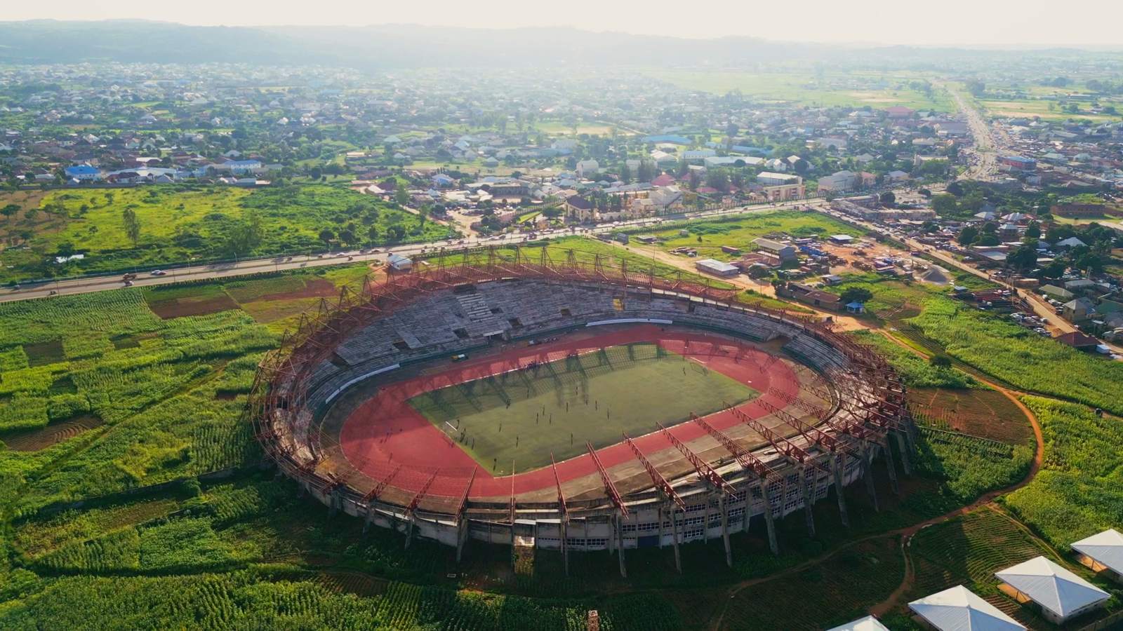Plateau United's home ground in Jos from the air: the oval bowl with its red running track and green pitch, ringed by farmland with the city beyond